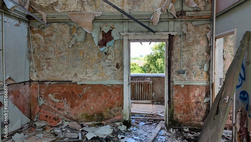 Crumbling plaster room walls, debris-covered floor, peeling wallpaper. Open balcony doorway falling apart. Derelict wrecked apartment contrast with nature outside. Urban decay interior disaster rubble
