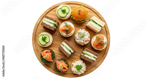 Assortment of elegant finger sandwiches and canapés arranged in a circular pattern on a wooden board, perfect for parties and events