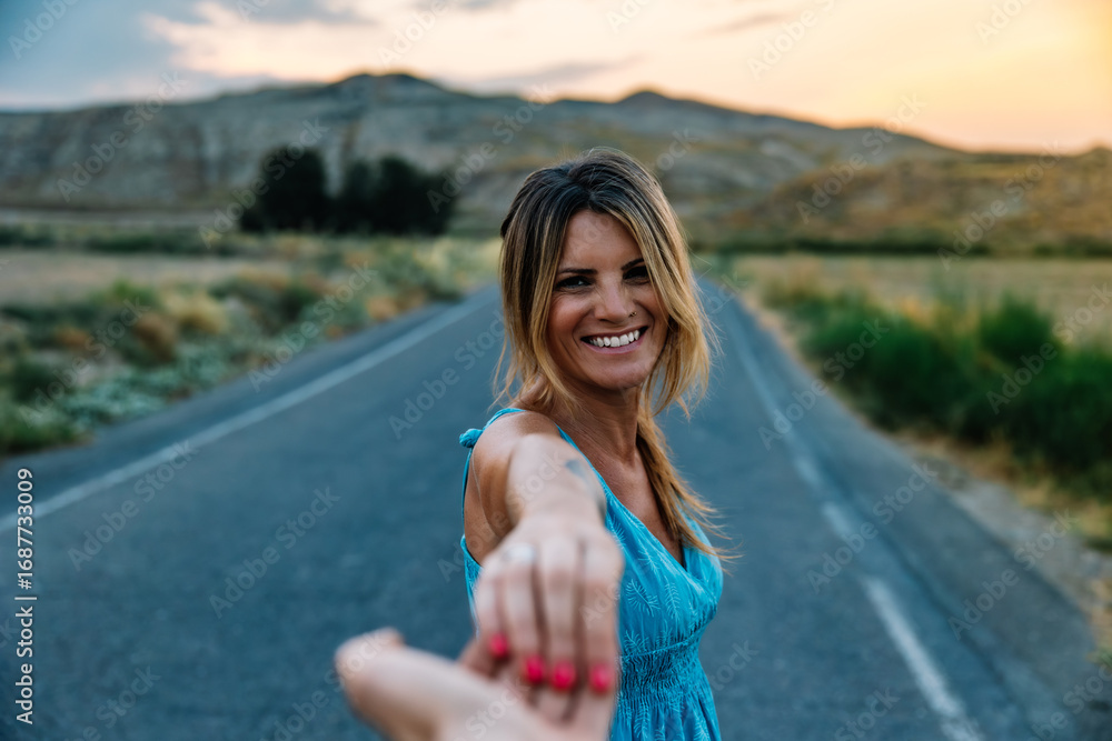 Naklejka premium Smiling woman leading partner by hand on scenic road trip