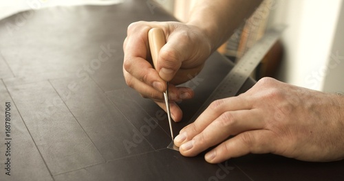 Fotografía Leather artisan hands marking corner lines on leather sheet with awl