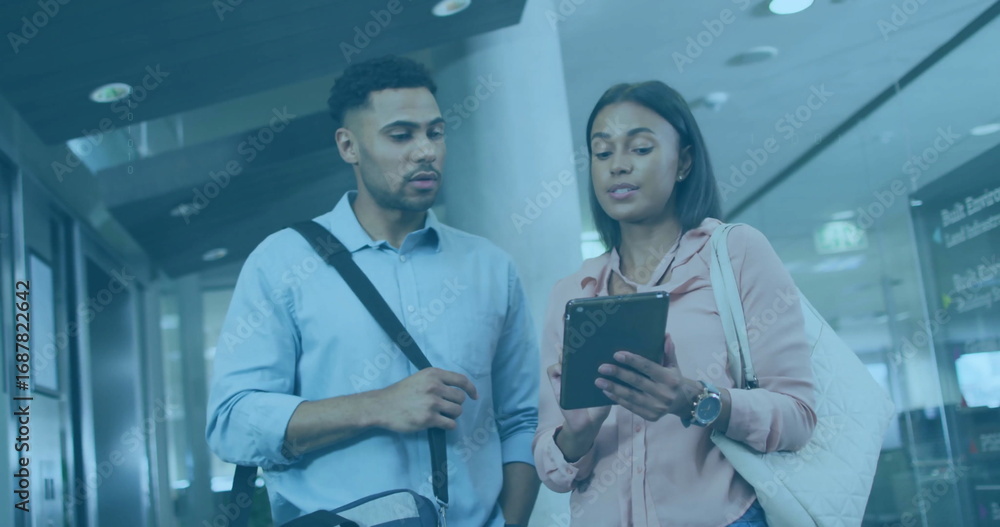 Obraz premium Couple reviewing tablet in departure hall, with messenger bag, tote bag and digital signage board