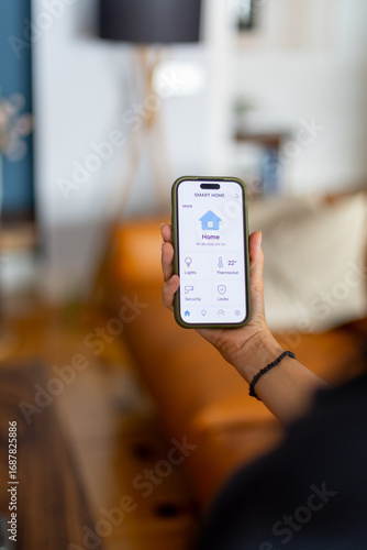 Woman holding smartphone and managing smart home devices