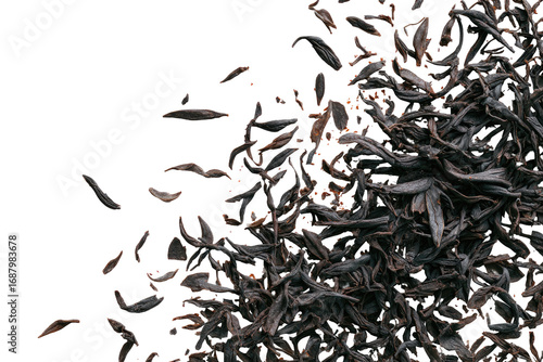Black tea leaves scattered against black background