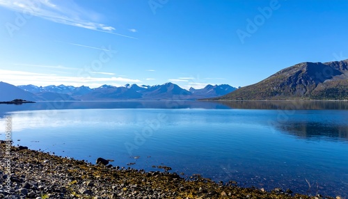 Wallpaper Mural A tranquil scene unfolds with a calm, reflective lake mirroring a clear blue sky and distant snow-capped mountains. Torontodigital.ca