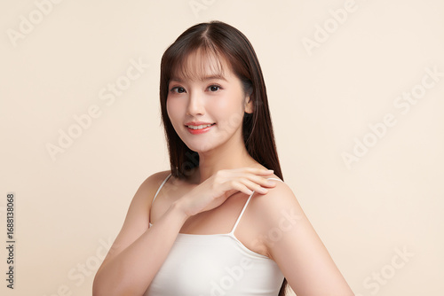 A beautiful young Asian woman with clean, fresh skin against a beige background. Skincare, facial treatment, cosmetology, beauty, and spa. An elegant portrait of an Asian woman.