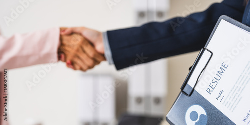 employer hr with employment contract job on desk officer hiring welcoming female asian newcomer worker manager shaking hands in contemporary office. Getting new job handshake concept.