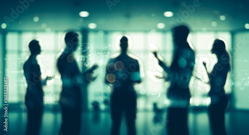 Silhouetted business people stand in a group discussion in a modern office.