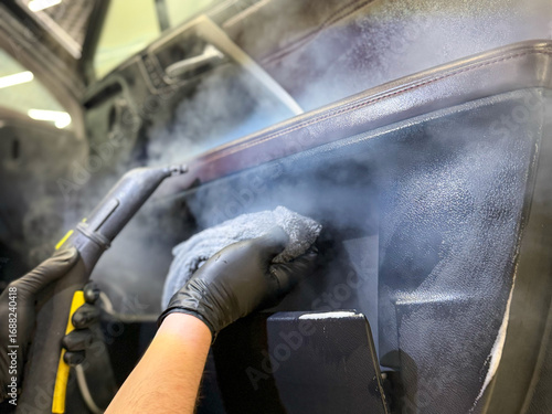 The concept of car detailing is the dry cleaning of the car interior. The detailing master cleans the car interior with a hot steam cleaner close-up. Dry cleaning of the car interior, close-up. 