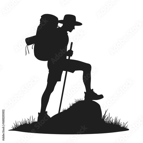 Silhouette of hiker with backpack and walking stick on grassy rock 1