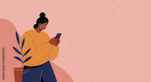 A young woman with dark skin and glasses, wearing a cozy sweater, is absorbed in her smartphone with a potted plant nearby.