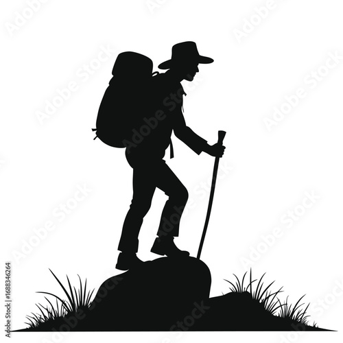 Silhouette of hiker with backpack and walking stick on rock