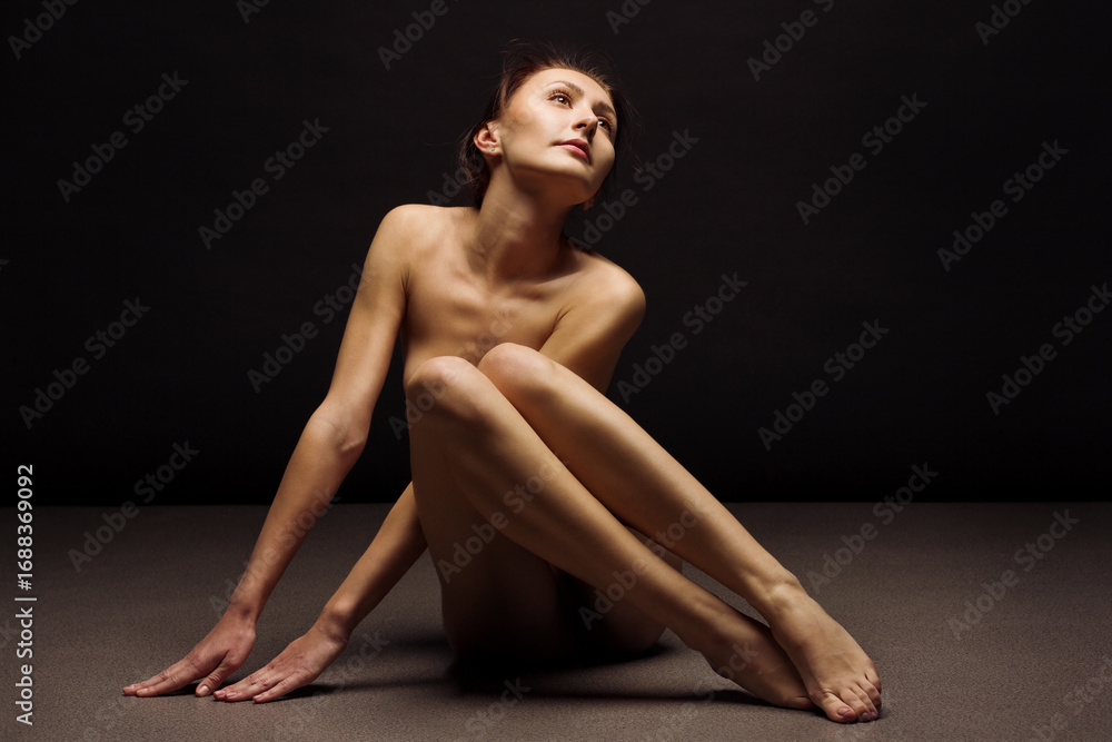 Fototapeta premium Beautiful lady sitting on black background 
