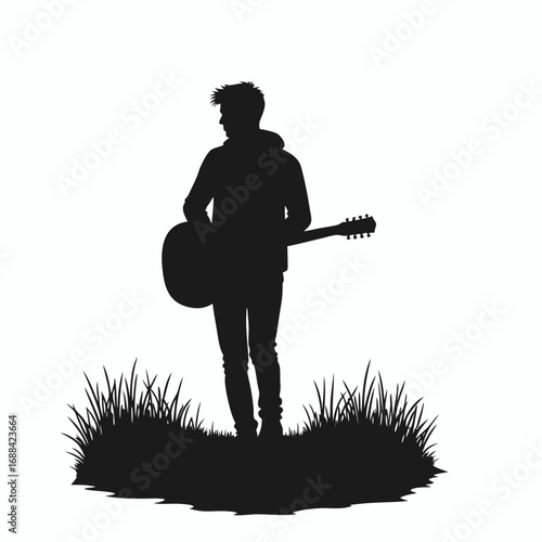Black silhouette of a young man with a guitar standing in grass