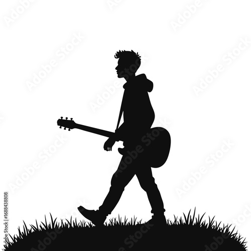 Silhouette of a young man walking with a guitar grass