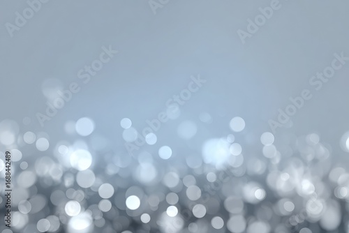 Abstract background features sparkling bokeh lights in grayscale, with a soft gradient fade to light blue at the top, evoking a dreamy or festive mood