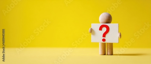 The wooden mannequin holding a question mark sign on bright yellow background