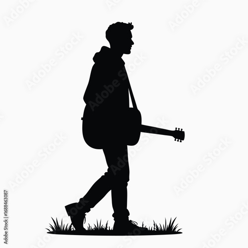 Black silhouette of a young man walking with a guitar