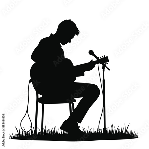 Silhouette of man playing acoustic guitar and singing into microphone outdoors