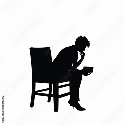 Silhouette of person sitting in chair holding book