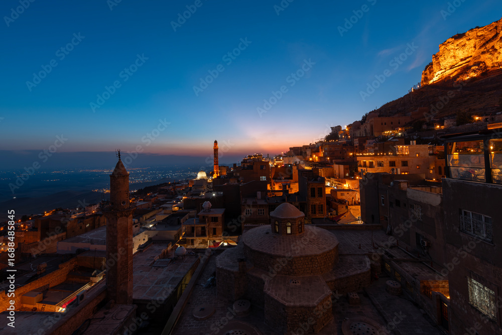 Obraz premium Mardin cityscape with roof of a Turkish hammam and minarets in Mardin old town at sunset, Mesopotamia, Turkey.