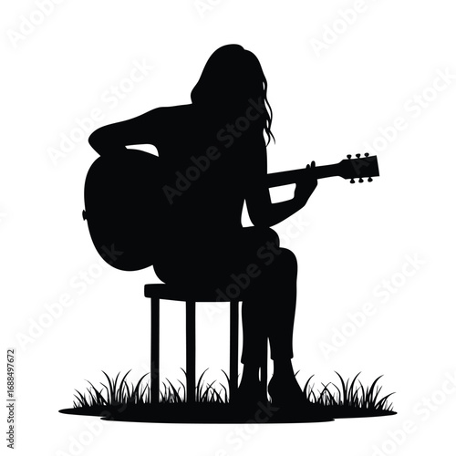 Silhouette of person playing acoustic guitar sitting on stool outdoors