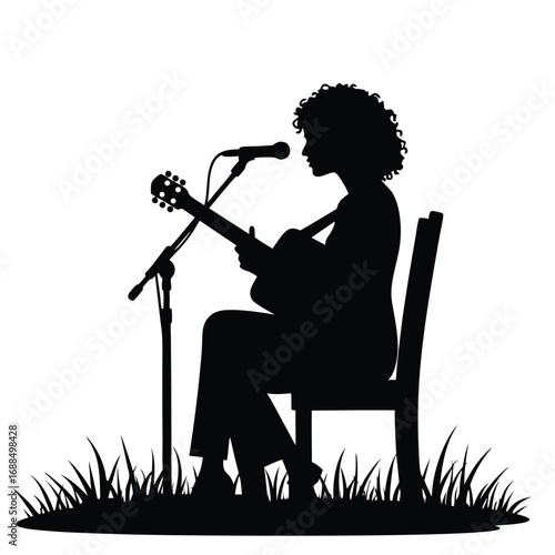 Silhouette of person playing acoustic guitar with microphone