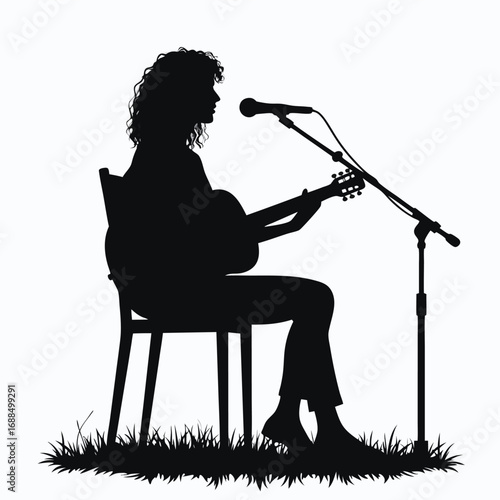 Silhouette of person playing guitar and singing into microphone