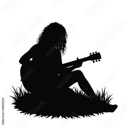 Silhouette of woman playing acoustic guitar in grass
