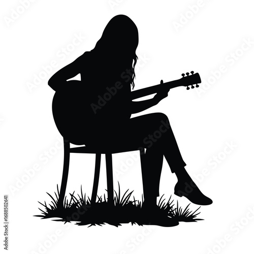 Silhouette of woman playing acoustic guitar sitting on chair in grass
