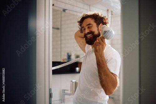Obraz na plátně Happy man drying his hair in bathroom.