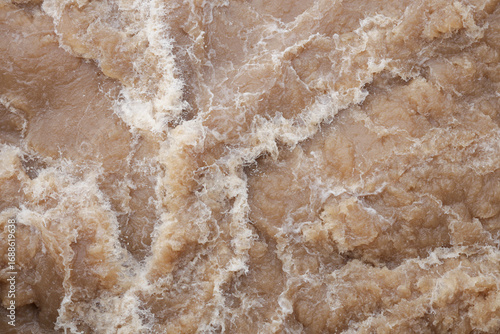 Background image of turbulent brown streams water. Brown water that is turbulent and produces a lot of foam.