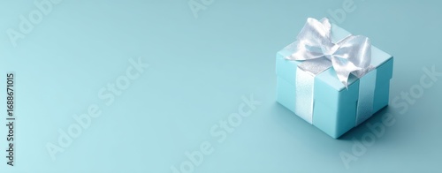 The gift box with white satin bow on pastel turquoise background for celebrations