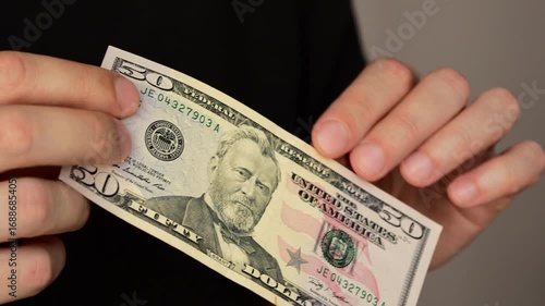 50 US dollars in the hands of a businessman.
Cash close-up.
Payment for goods and services in cash.
Expensive purchases and spending money.
Shopping and finances