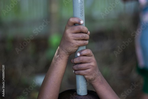 Childs hands gripping a grey pole outdoors