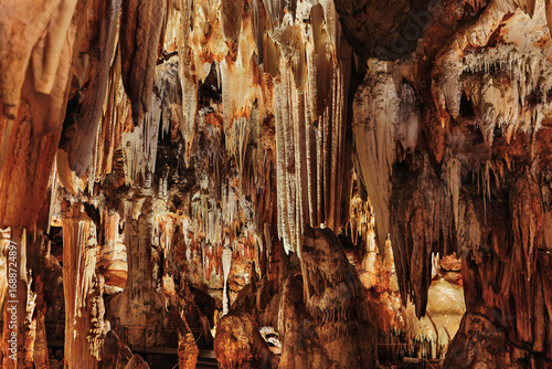 Panoramic view of stalactites and stalagmites in an artificially lit underground cave