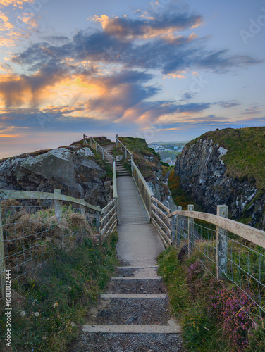 Gobbins Cliff Path in Nordirland – schmaler Brückenpfad zwischen Felsen mit Blick auf die Küste bei Sonnenuntergang