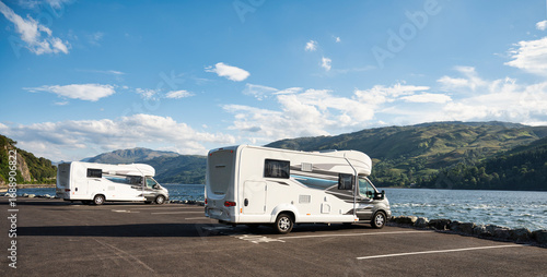 Motorhomes parked by scenic lake in Scotland during summer road trip in the highlands
