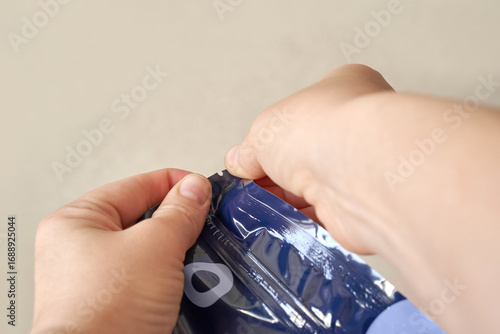 Close-up of hands opening a plastic snack bag with tear notch for easy access and convenience.
