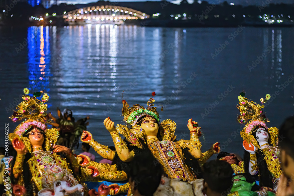 Obraz premium Durga Puja Visarjan festival celebration with beautifully decorated idols immersed in Hooghly river kolkata at night with illuminated bridge lights reflection