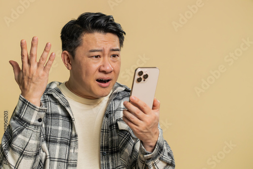 Obraz na plátně Upset sad Asian man use smartphone typing browsing, play game, loses, surprised by sudden lottery results bad fortune loss fail unlucky news
