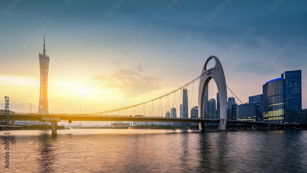 Naklejka premium Beautiful sunset view of modern bridge and skyscrapers by the river