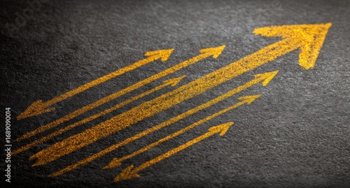 Angled shot of upward trending yellow arrows drawn on a dark textured surface, hinting at growth and progress