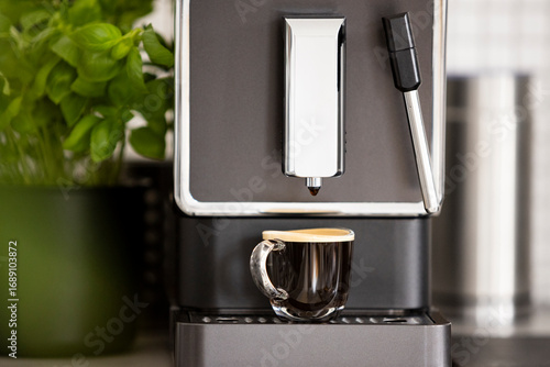 Close-up of a double espresso in a transparent glass cup made in a home coffee maker. Strong black coffee with golden crema, ideal for café, breakfast, or lifestyle concept.