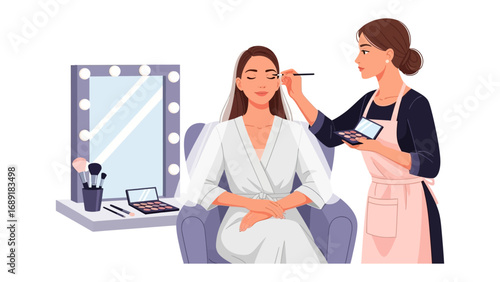 Professional makeup artist applying eye makeup to a woman in a white robe in a well lit vanity area