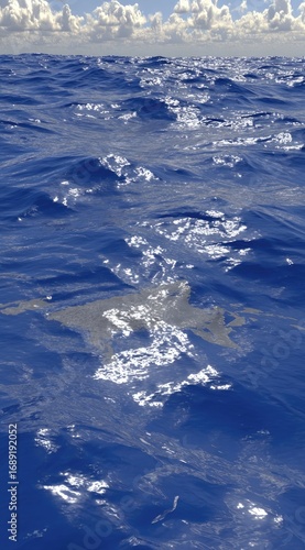 A shimmering expanse of deep blue ocean water reflects sunlight under a cloudy sky, creating a sense of vastness and serene beauty