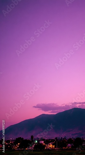 Soft, purple sky over a mountain ridge silhouetting a distant city. Soft focus lends a dreamlike quality to the scene