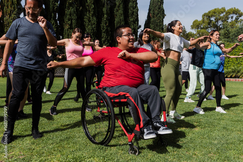 Large Group of Latin sporty multi age people and disabled man in wheelchair in Zumba class outdoors in a public park in Mexico Latin America. Diverse group in social inclusion concept