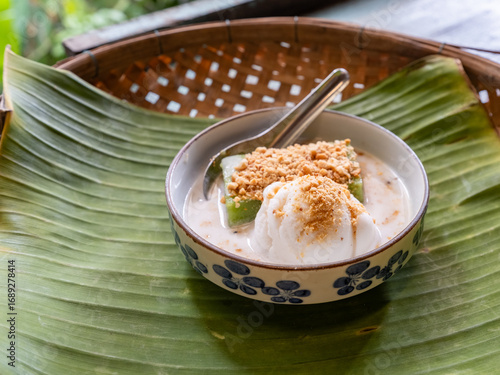 Traditional Thai coconut ice cream topped with crushed peanuts, served with coconut milk and Thai dessert on a banana leaf. Authentic Thai dessert with refreshing and sweet flavor.