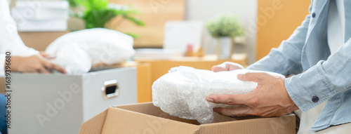 Tableau sur toile Happy woman checking stuff in cardboard box before sent to transportation company and moving to new location apartment