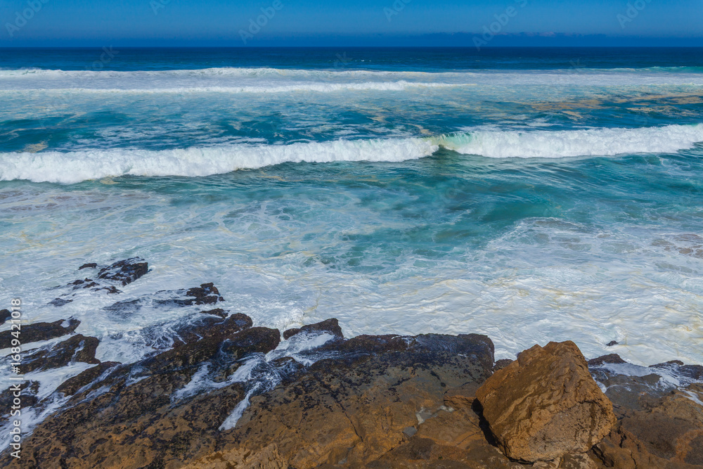 Powerful waves crash against rugged coastal rocks Powerful waves crash against rugged coastal rocks